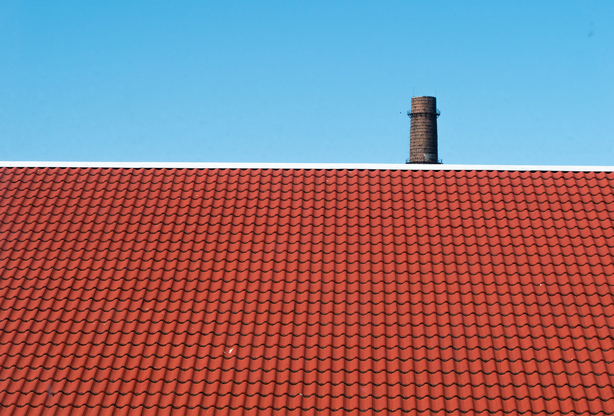Red tile roof with chimney against the blue sky